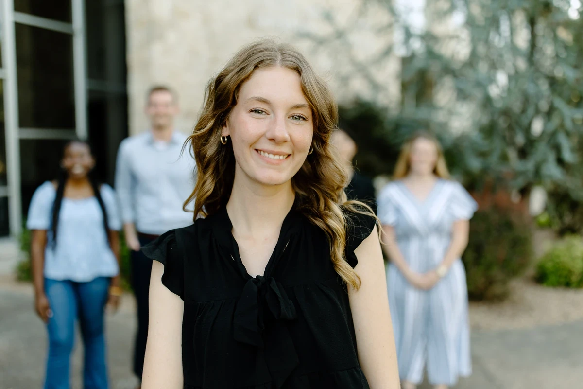 A woman in a black dress smiles at the camera.